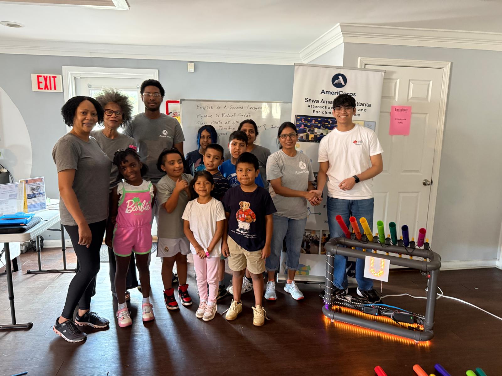 Hrehaan and BoomBot leading an interactive music & robotics activity with smiling elementary students
